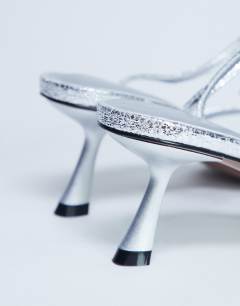 Model wearing Ila toe loop mid heel sandal in silver