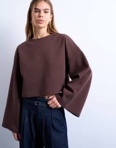 Model wearing Interlock long wide sleeve top in chocolate brown