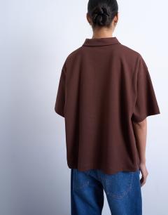 Model wearing Interlock short sleeve polo tee in chocolate brown