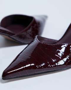 Model wearing Ivette croc patent close toe mule in burgundy
