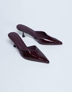 Model wearing Ivette croc patent close toe mule in burgundy