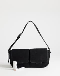 Model wearing Joanie small shoulder bag with front pockets in black suedette