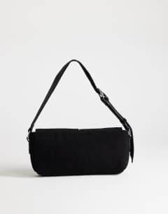 Model wearing Joanie small shoulder bag with front pockets in black suedette
