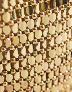 Model wearing Junoe small beaded wristlet grab bag in gold
