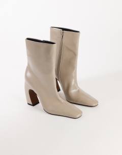 Model wearing Karter curved heel ankle boot in mink stretch faux leather