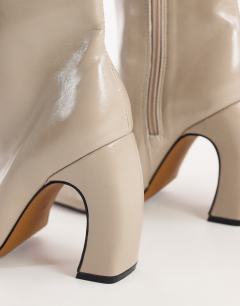 Model wearing Karter curved heel ankle boot in mink stretch faux leather
