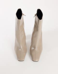Model wearing Karter curved heel ankle boot in mink stretch faux leather