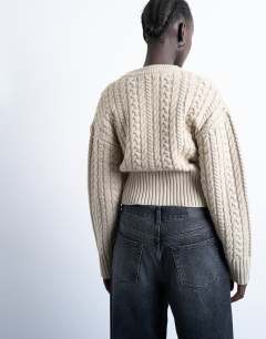 Model wearing Knitted cable fitted waist cardigan in oat