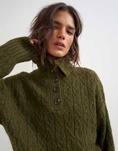 Model wearing Knitted cable stitch funnel neck jumper in moss