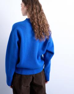 Model wearing Knitted chunky all needle clean crew jumper in Blue