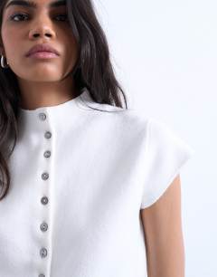 Model wearing Knitted compact cap sleeve waistcoat in Ivory