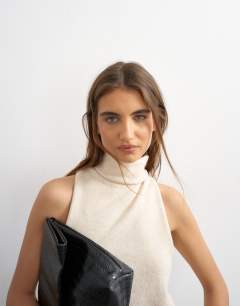 Model wearing Knitted high funnel neck sleeveless twist back top in latte