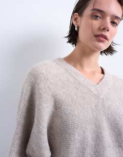 Model wearing Knitted high v horizontal stitch jumper in oat