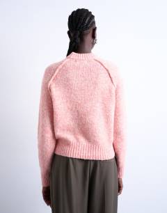 Model wearing Knitted raglan exposed seam jumper in pink
