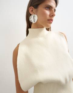 Model wearing Knitted sculpted sleeveless funnel neck jumper in ivory