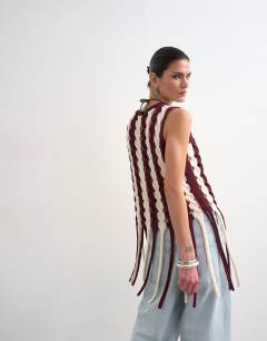 Model wearing Knitted sleeveless longline knit top with tassel fringe hem in burgundy