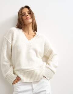 Model wearing Knitted v neck slouchy roll seam detail jumper with wool in ivory