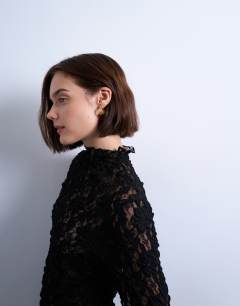 Model wearing Lace high neck long sleeve asymmetric hem top in black