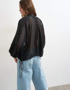 Model wearing Lace trim ruched side blouse in black