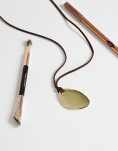 Model wearing Leila cord necklace with pendant in gold and brown