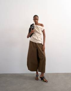 Model wearing Linen cinched waist asymmetric twist shoulder top in natural
