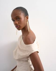 Model wearing Linen cinched waist asymmetric twist shoulder top in natural