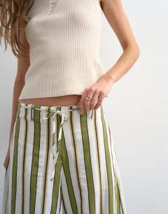 Model wearing Linen green stripe clean tie waist barrel trouser in green