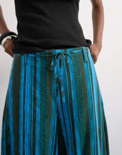 Model wearing Linen stripe clean tie waist barrel trouser in blue