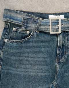 Model wearing Low rise belted jean in mid blue