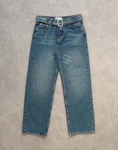 Model wearing Low rise belted jean in mid blue