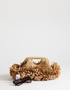 Model wearing Mabel straw fringe clutch in natural
