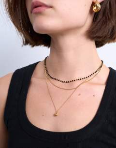 Model wearing Maddox stainless steel multi chain necklace with black beads in gold