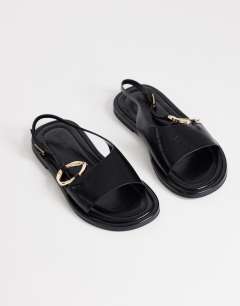Model wearing Mandy round toe flat sandal with hardware in black