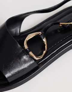 Model wearing Mandy round toe flat sandal with hardware in black