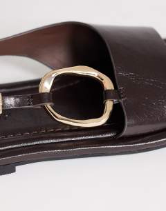 Model wearing Mandy round toe flat sandal with hardware in chocolate