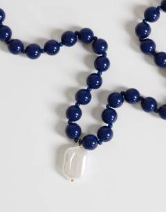 Model wearing Marais beaded necklace with pearl charm in blue and white faux marble