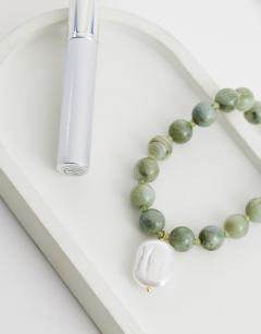 Model wearing Marais beaded necklace with pearl charm in green and white faux marble
