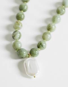 Model wearing Marais beaded necklace with pearl charm in green and white faux marble