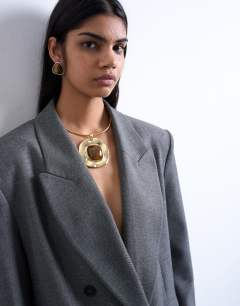 Model wearing Max statement necklace in gold with brown stone