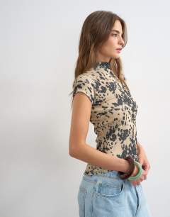 Model wearing Mesh animal cap sleeve top in cow print
