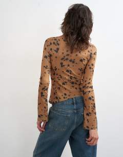 Model wearing Mesh high neck ruffle button long sleeve top in deer print