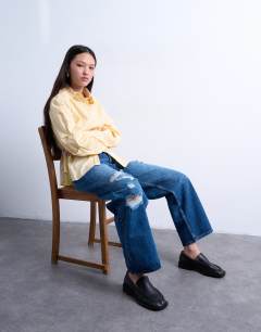 Model wearing Mid rise cinch jean with knee rip in mid blue