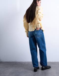 Model wearing Mid rise cinch jean with knee rip in vintage blue