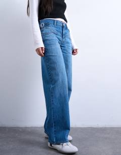 Model wearing Mid rise yoke front cinch jean in mid blue