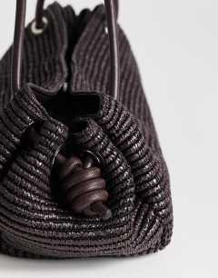Model wearing Miller large straw shoulder bag in chocolate