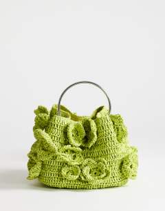 Model wearing Millie small straw flower grab bag with metal handle in lime