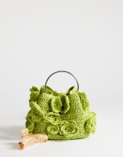 Model wearing Millie small straw flower grab bag with metal handle in lime