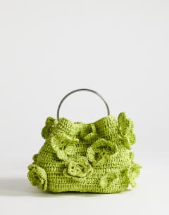 Model wearing Millie small straw flower grab bag with metal handle in lime