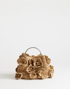Model wearing Millie small straw flower grab bag with metal handle in natural