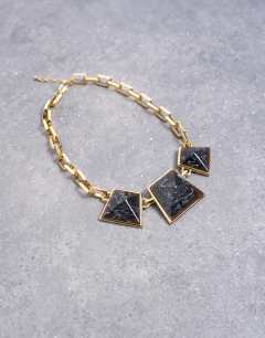 Model wearing Milo statement necklace in gold and black